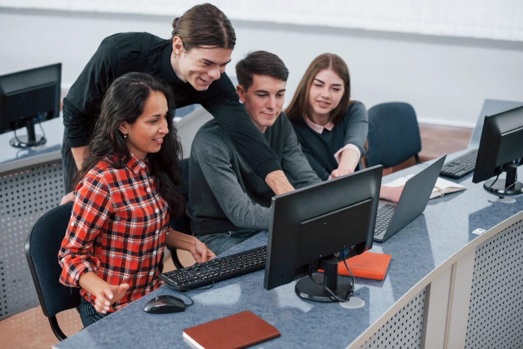 Group of students collaborating on a computer project in a classroom lab.